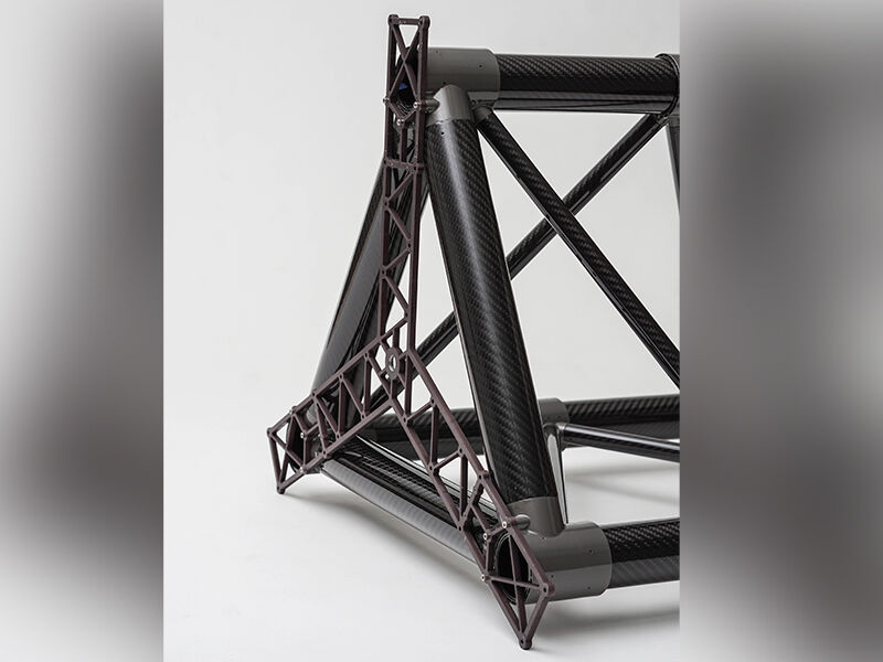 Close up image of the end of the truss structure. The primary structure is triangular in shape and laying on its side, and the image crops off most of the structure. There are truss-like substrates radiating from the center of the truss and that are attached to the three primary posts. The structure is on a white background.